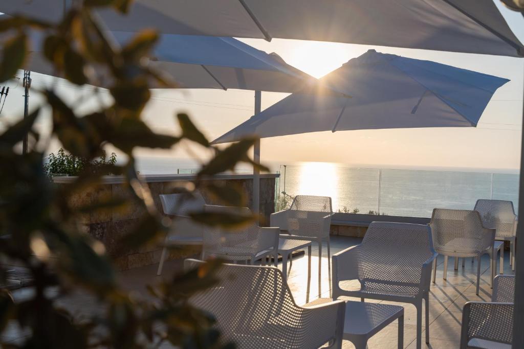 une terrasse avec des chaises et des parasols et l'océan dans l'établissement Villa Rocca - Rooms&SPA, à Pizzo