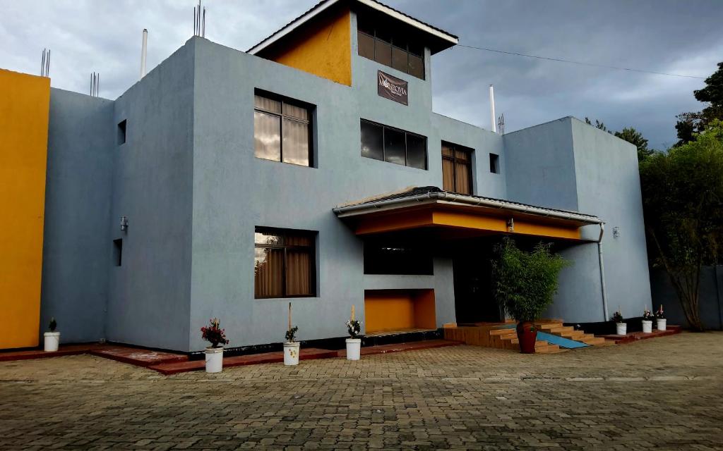 a blue and yellow house with a lot of windows at Monrovia Guest House in Nakuru