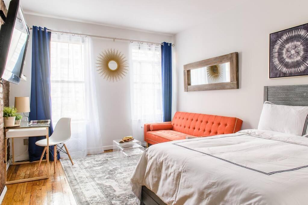1 dormitorio con 1 cama y 1 sofá naranja en 26-3A STUDIO Gramercy W D Outdoor Courtyard, en Nueva York