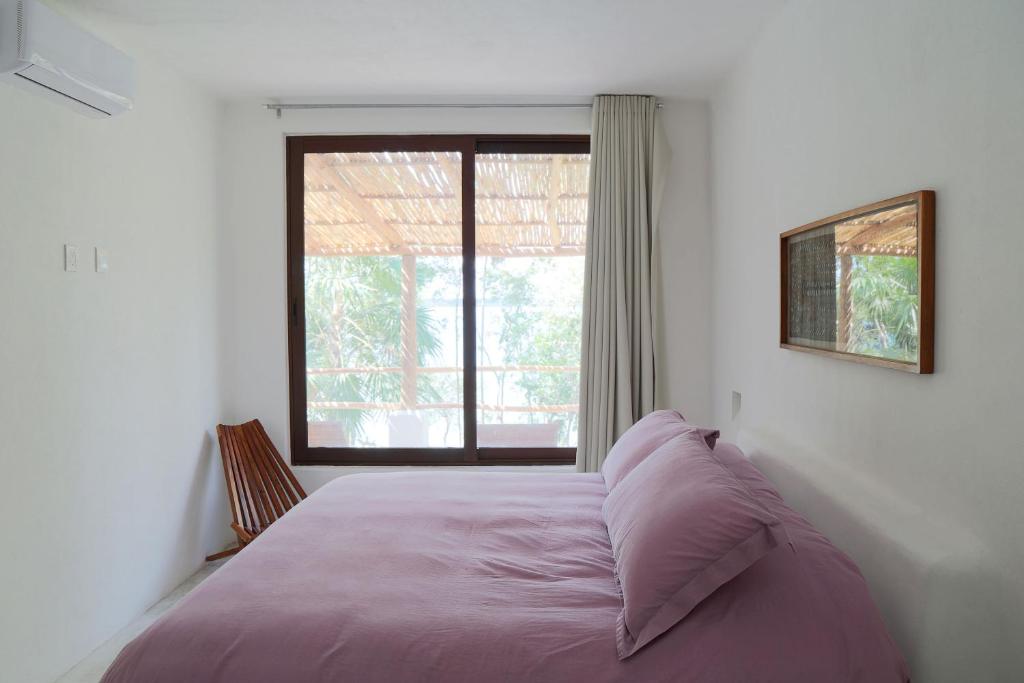 1 dormitorio con 1 cama y ventana grande en Casa Marivan, Private Pier, Free Paddle Boards & Kayac en Bacalar