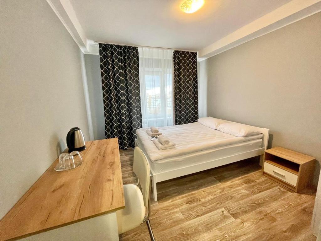 um pequeno quarto com uma cama e uma secretária em Hotel 7F em Kiev