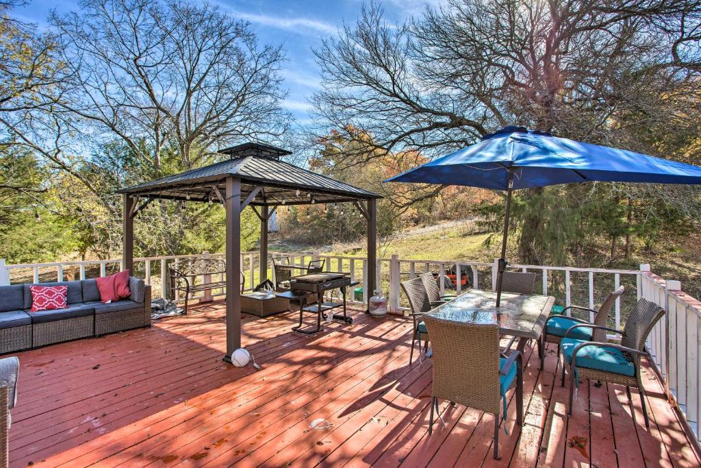 una terraza de madera con mesa y sombrilla azul en Serene Blue Cottage on Majestic Acres Ranch, 