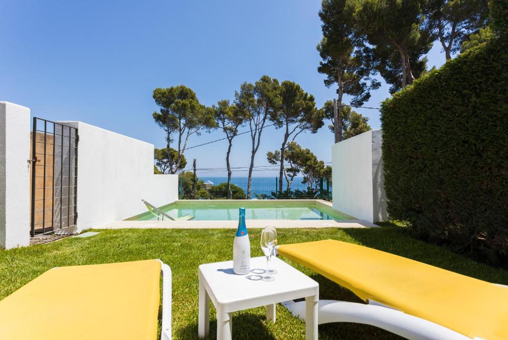 żółty stół, 2 krzesła i butelka wina w obiekcie Luxury villa in front of the beach ONA w mieście Calella de Palafrugell