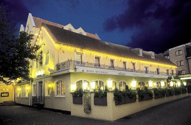 un gran edificio blanco con luces encendidas por la noche en Hotel Restaurant Höttche, en Dormagen