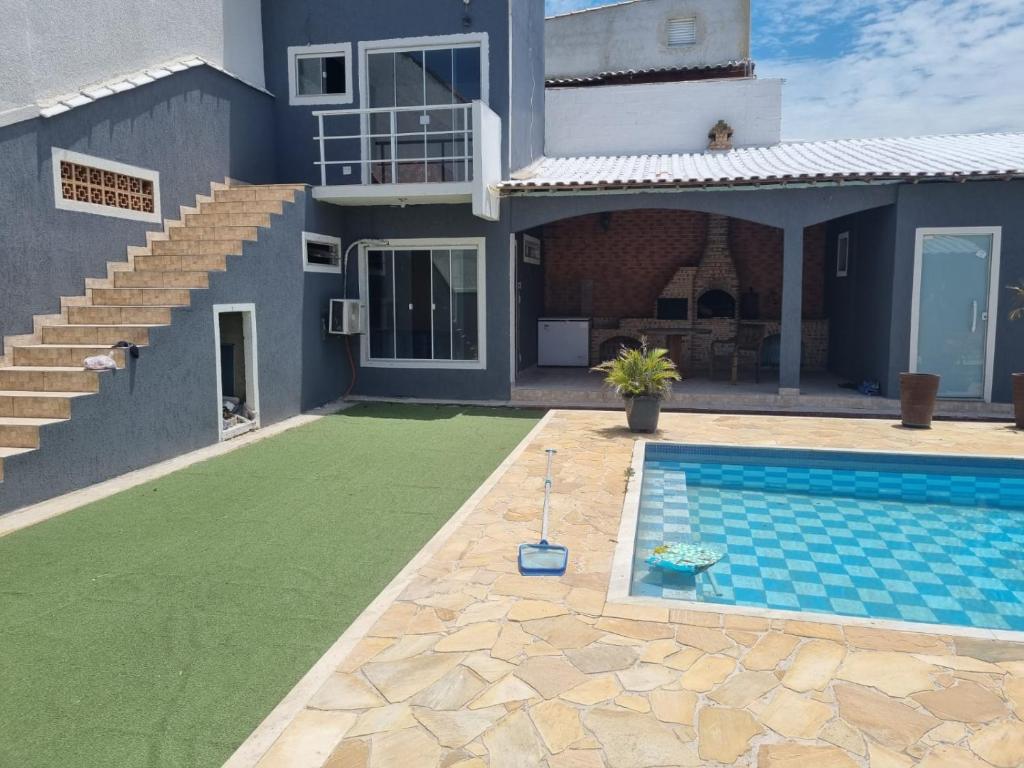 a villa with a swimming pool in front of a house at Pousada Litorânea in Saquarema