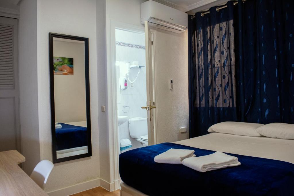 a bedroom with a bed and a bathroom with a mirror at Hostal Ártico in Madrid