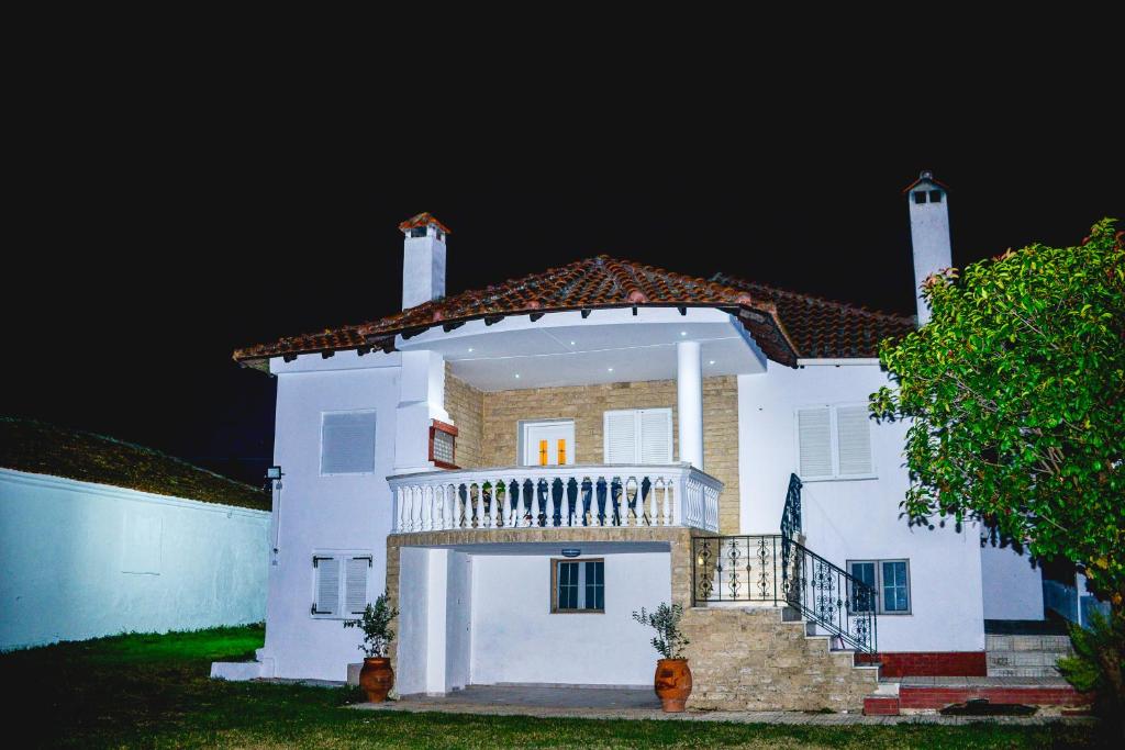 a large white house with a balcony at night at Bastasio airport skg in Tagarades