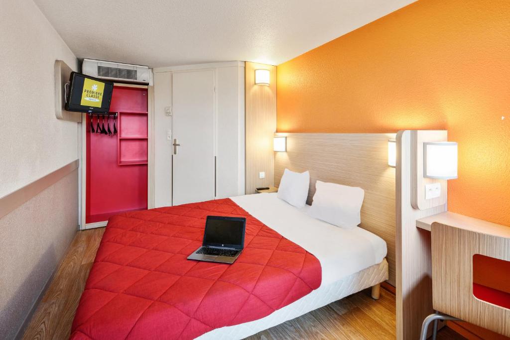 une chambre d'hôtel avec un lit et un ordinateur portable. dans l'établissement Premiere Classe Metz Sud Jouy Aux Arches, à Jouy-aux-Arches