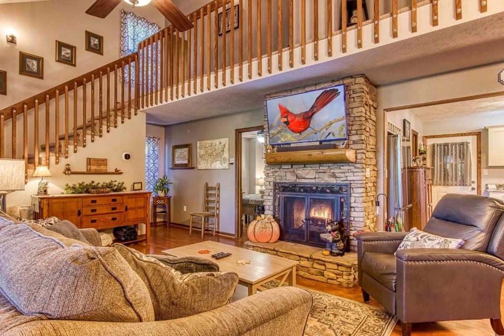 a living room with a stone fireplace and a staircase at Cozy Cabin with Mountain Views Near SkyLift Park! in Gatlinburg