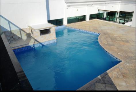 una grande piscina di acqua blu in un edificio di Loft Prainha ad Arraial do Cabo