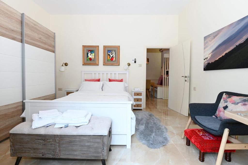 a bedroom with a white bed and a chair at Josephine's 2Bdrm apt 50M to Bahai gardens in Haifa