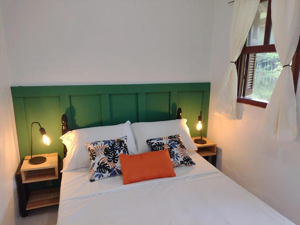 um quarto com uma cama branca e uma almofada laranja em Lago 7 Cores em Tapiraí