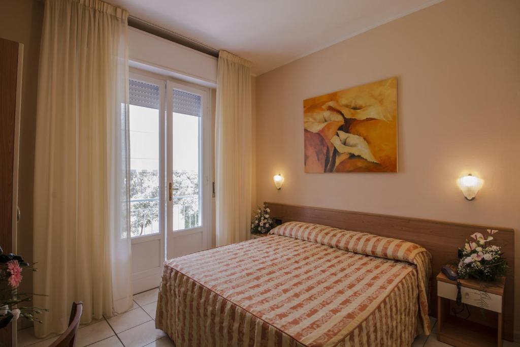 a bedroom with a bed and a large window at Hotel Riviera Blu in Tirrenia
