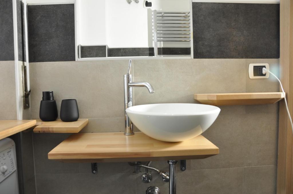 a bathroom with a white bowl sink on a wooden counter at C Studio - Design Bilo Suite -M3- 8 min dal Duomo in Milan