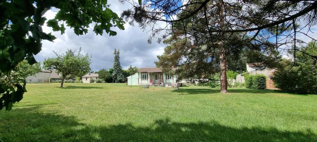 une maison dans une cour avec une pelouse verte dans l'établissement Chalet au calme en forêt, à Coye-la-Forêt