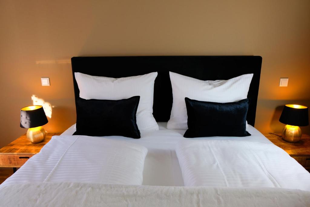 a bed with black and white pillows and two lamps at Design Apartment Nr 1 mit Terrasse und Parkplatz in Straubing