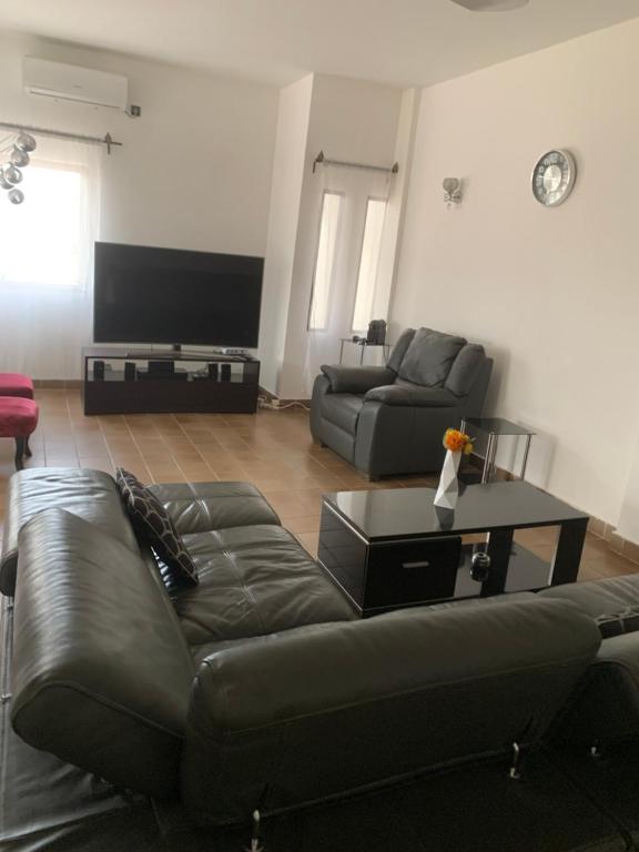a living room with a leather couch and a table at Luxious Cosy Apart 2 Bedroom Cotonou Centre in Cotonou