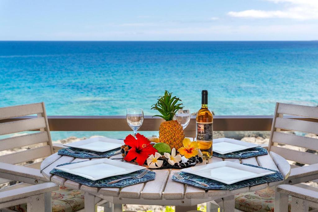 - une table avec une bouteille de vin et de l'ananas sur la plage dans l'établissement Keauhou Kona Surf & Racquet Club #5-202, à Kailua-Kona