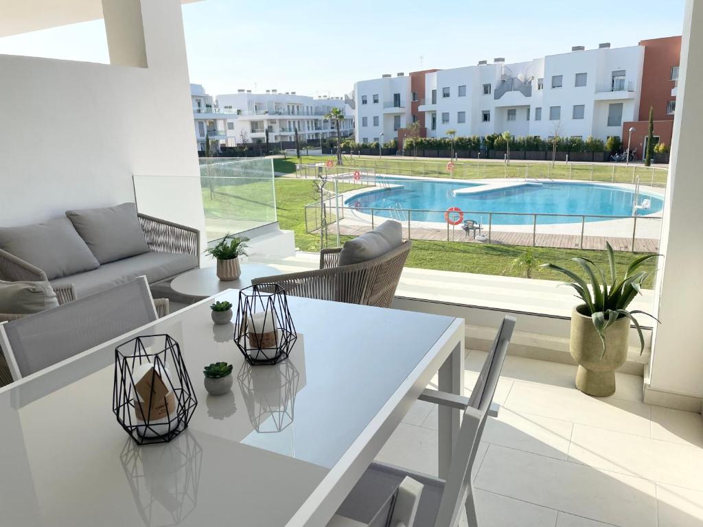 a white table and chairs in a living room with a pool at Apartamento en Costa Ballena in Chipiona