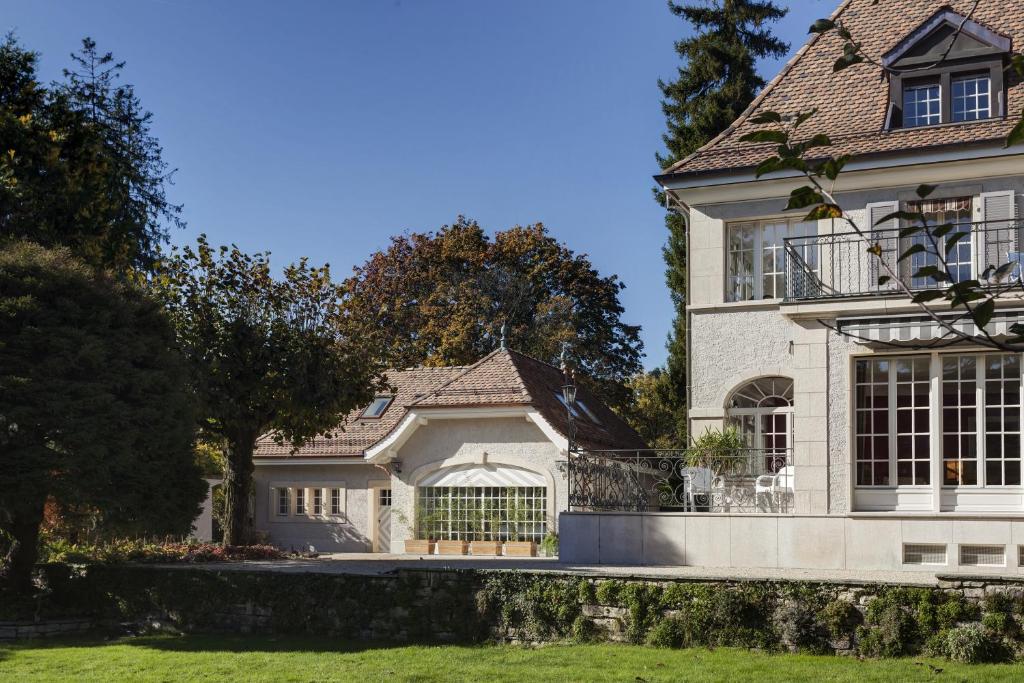 een groot wit huis met een dak bij Le Jour et la Nuit in Genève