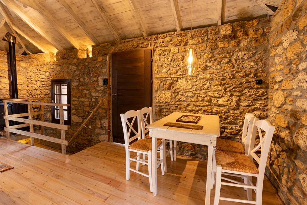 a table and chairs in a room with a stone wall at Managraia in Makrýgialos