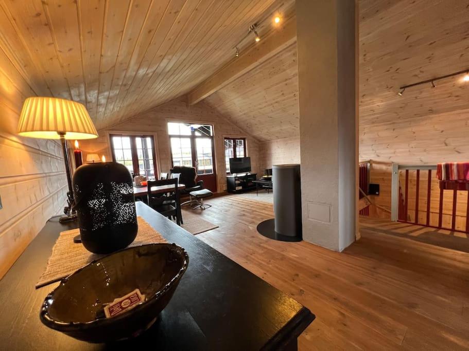 a living room with a wooden ceiling and a table at Fin leilighet rett ved skistadion in Beitostøl