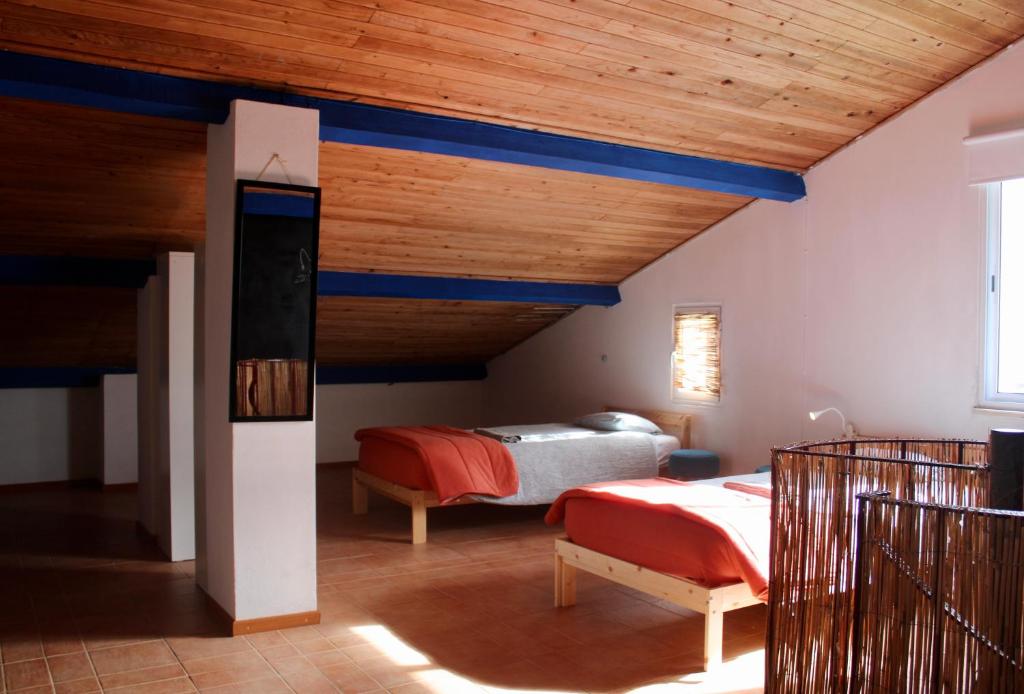 a bedroom with two beds and a wooden ceiling at Azores Bagus Surf House in Ponta Delgada