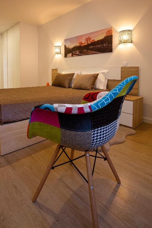 a bedroom with a bed with a chair in front of it at Apartamento C&C in Arcos de Valdevez
