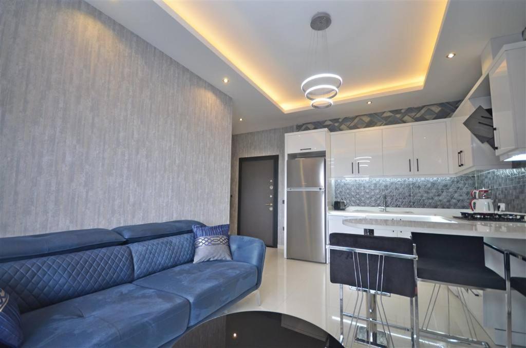 a living room with a blue couch and a kitchen at Апартаменти в готельному комплексі in Alanya