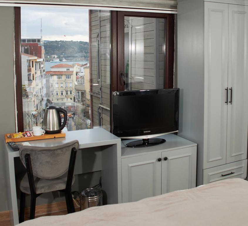 um quarto com uma televisão numa secretária com uma janela em Ortakoy Aysem Sultan Hotel em Istambul