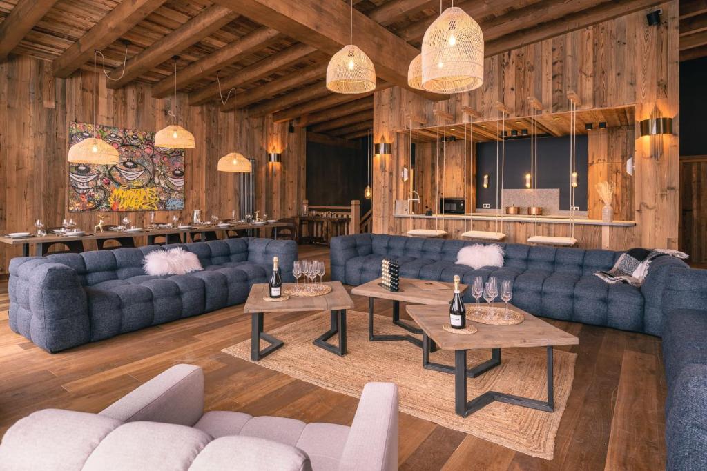 a living room with blue couches and tables at Chalet Amis - Meribel - Pool moovie and play room in Méribel