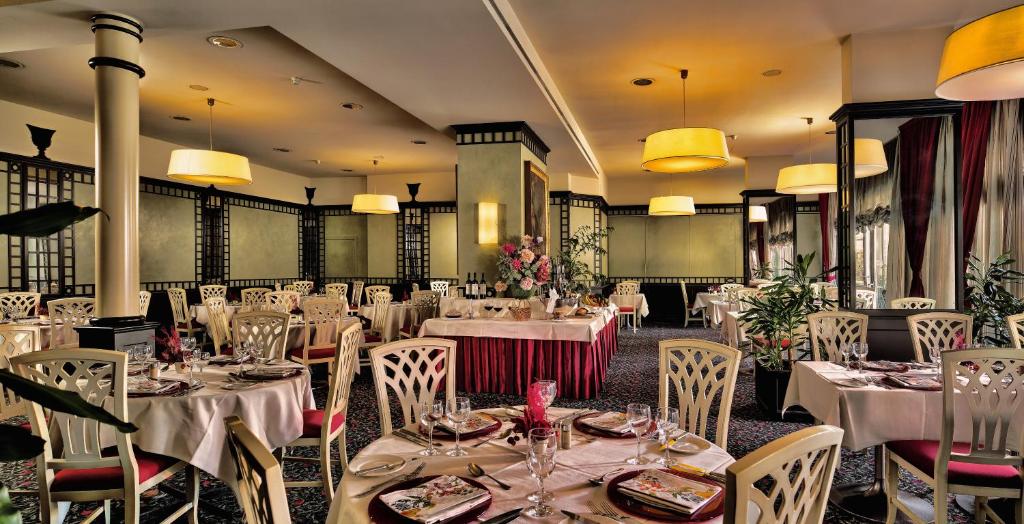 uma sala de jantar com mesas e cadeiras brancas em Hotel De La Paix em Lugano