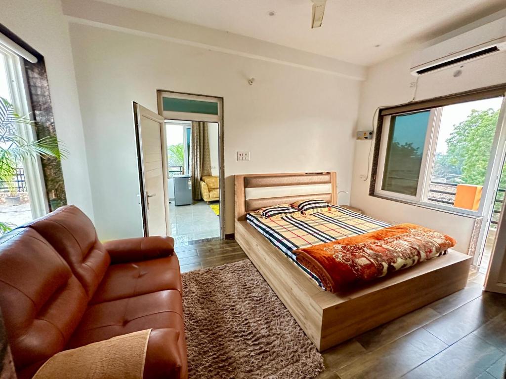 a bedroom with a bed and a couch and a chair at Kaashi Flora - Luxury 3BHK in Varanasi
