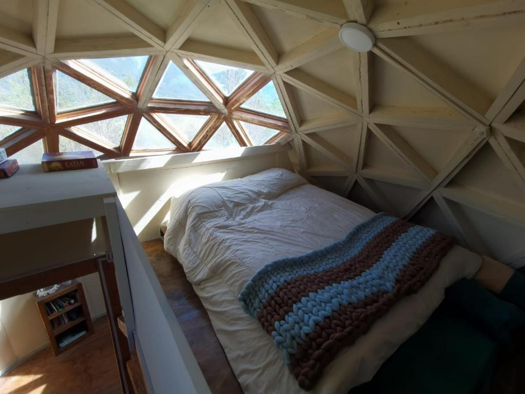 uma cama num quarto com uma grande janela em Alquimia del Hualle em Melipeuco