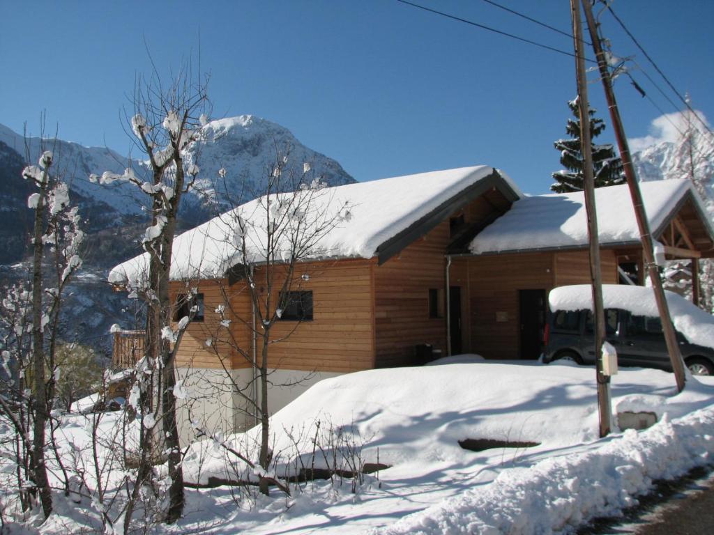uma cabana com neve no telhado e um carro estacionado na frente em Chalet de l'Infernet em Auris