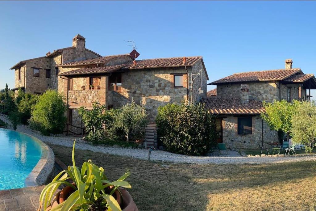 una gran casa de piedra con una piscina frente a ella en Country House - La casetta nel borgo, en San Venanzo