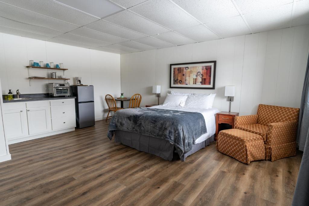 een slaapkamer met een bed en een stoel en een keuken bij Cuyuna Lakes Stay in Deerwood