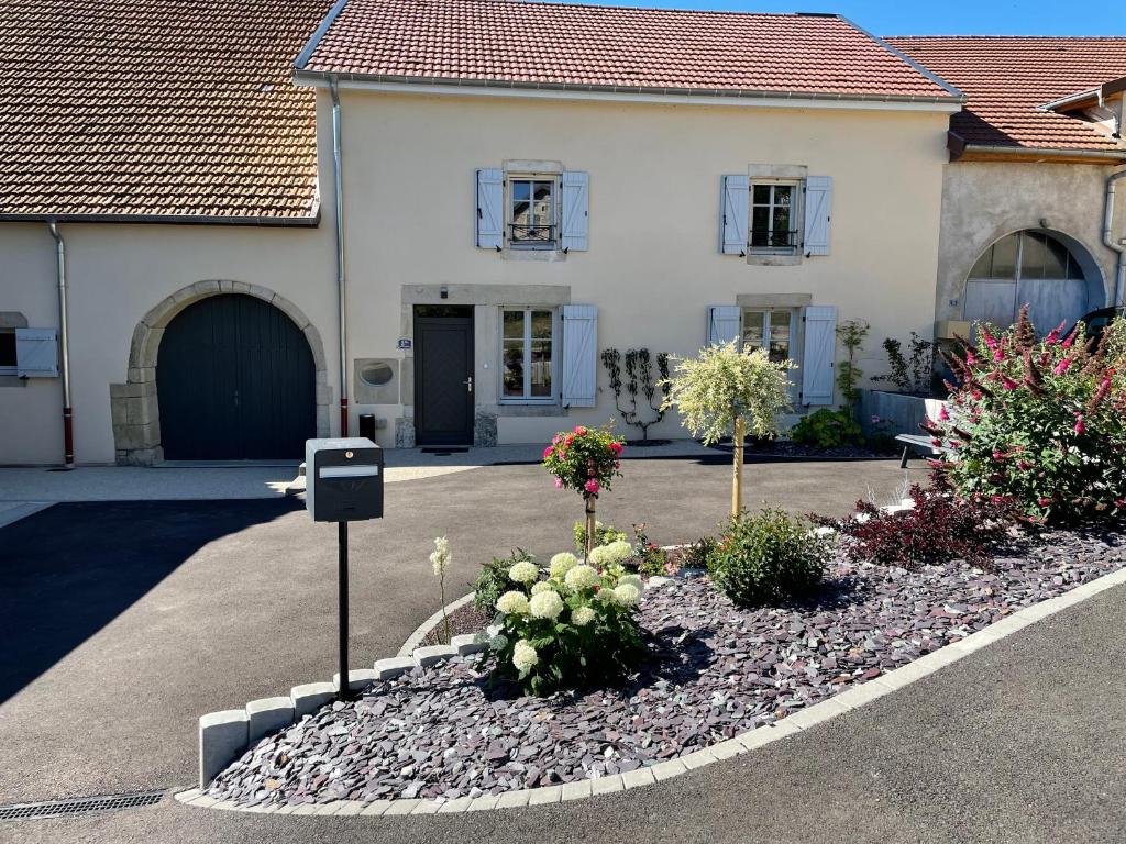 a white house with flowers in a driveway at Chez la Rose luxueuse cottage avec jacuzzi in Rouvres-la-Chétive