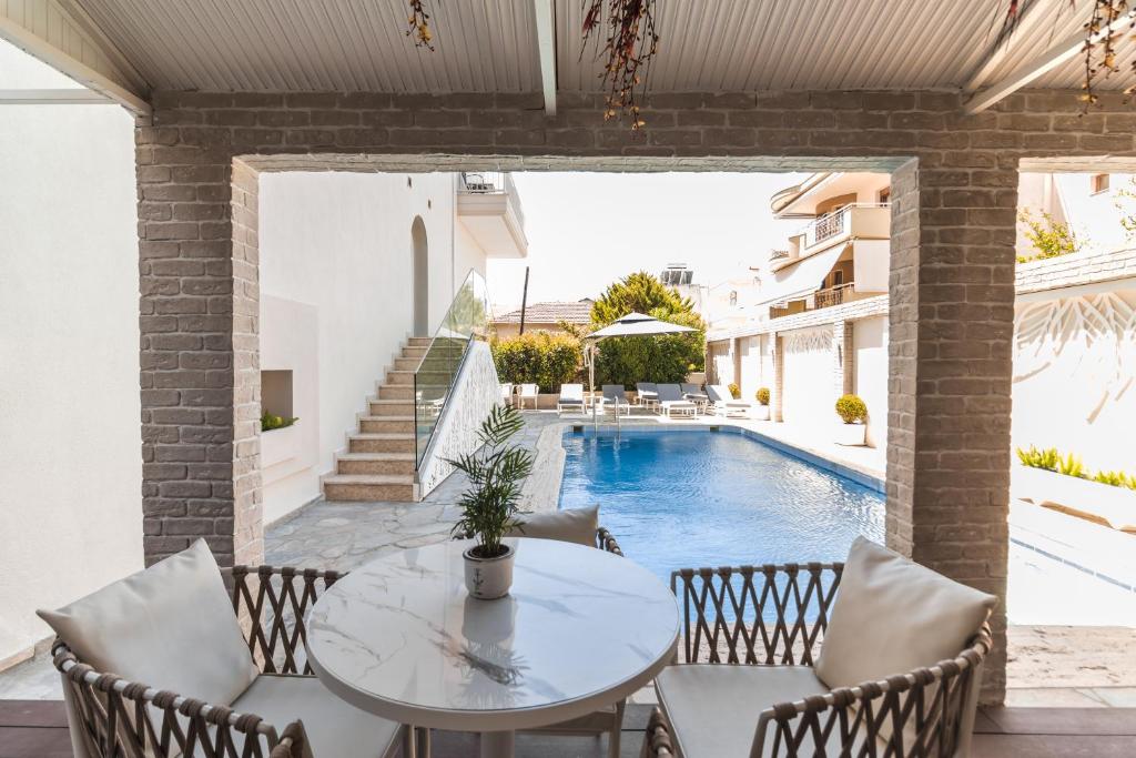 a patio with a table and chairs next to a swimming pool at Alkyonis Hotel in Nea Kallikrateia
