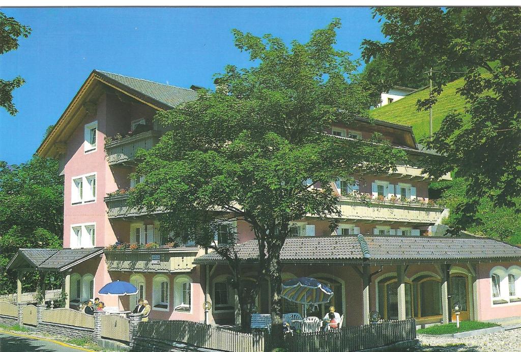 un edificio rosa con un albero di fronte di Residence Alpenrose a Sesto