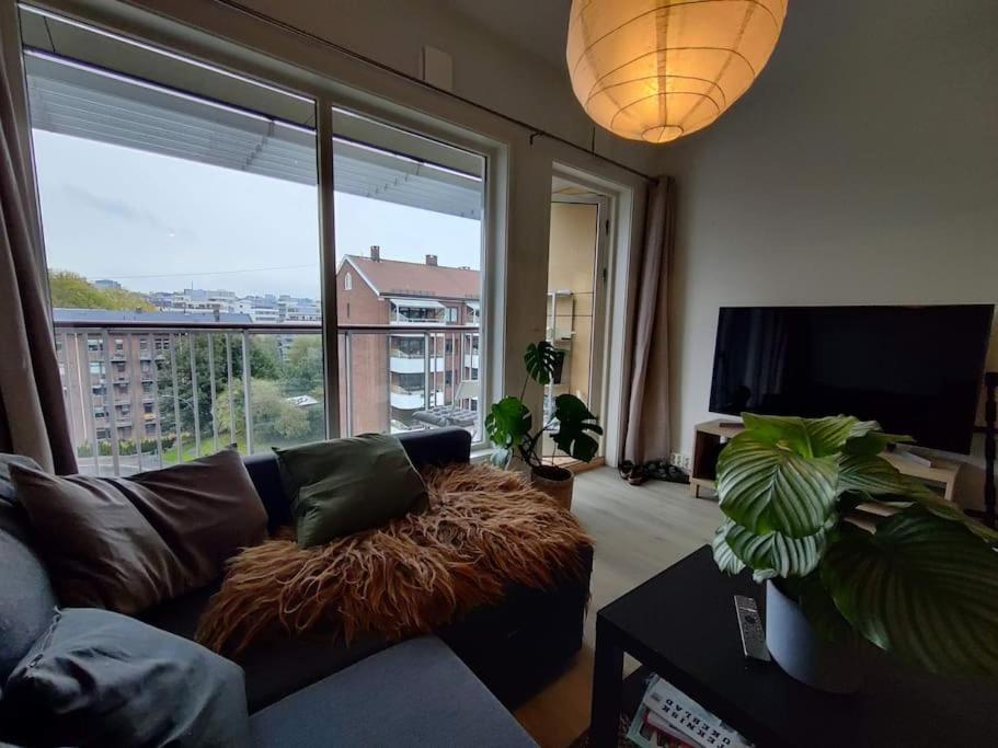 a living room with a couch and a large window at Spacious and cozy study apartment with balcony in Oslo