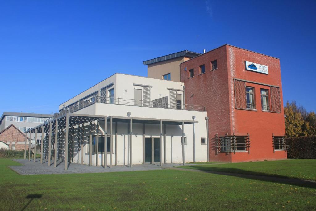 a building with a grassy field in front of it at Mondo hôtel in Tubize