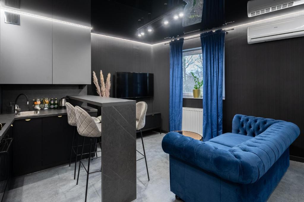 a living room with a blue couch and a kitchen at Apartament NEGRO Gliwice - nowe osiedle, klimatyzacja, parking in Gliwice