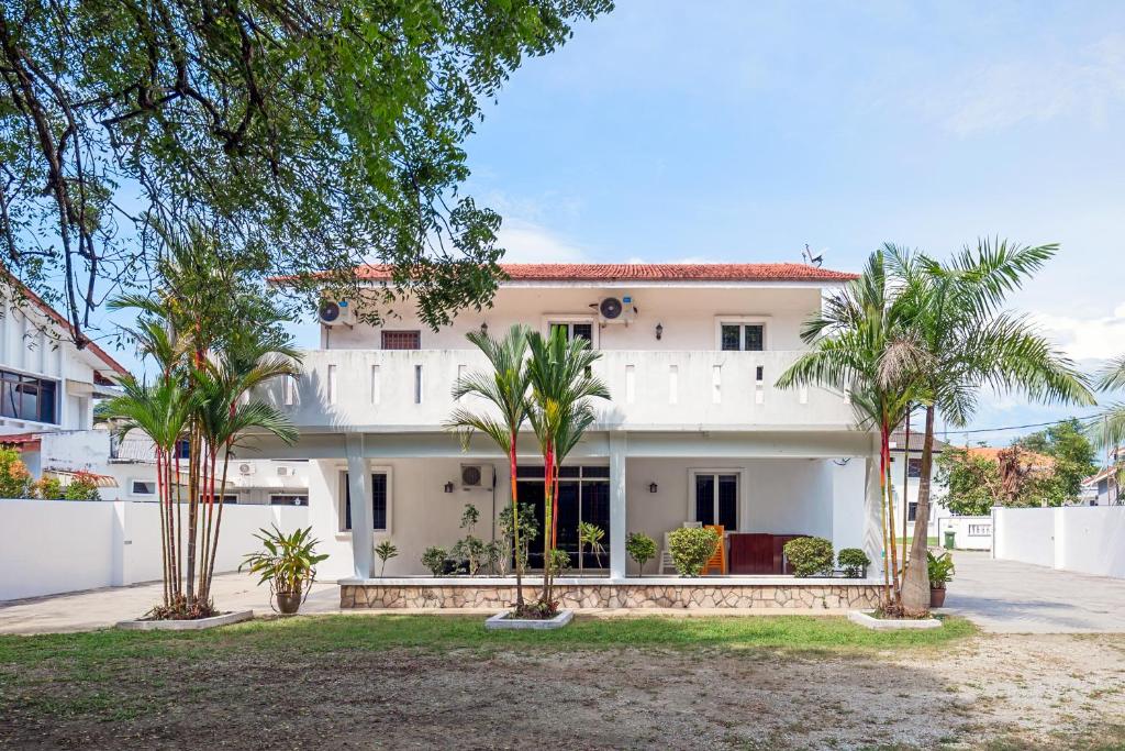 a white house with palm trees in front of it at Seaside Private Bungalow, Tg Bungah in Tanjung Bungah