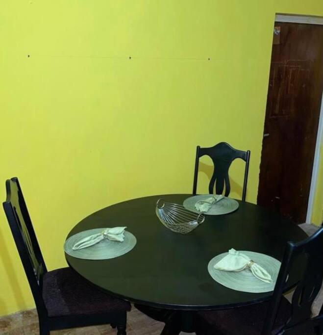una mesa de comedor verde con platos y sillas en Kingstonspot876, en Kingston