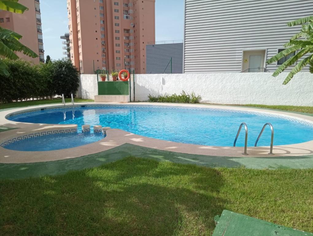 a swimming pool in a yard with tall buildings at Benidorm in Benidorm