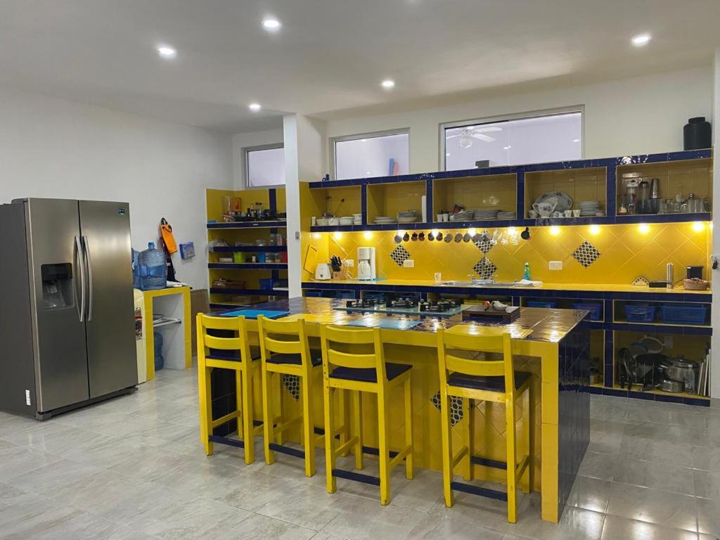 a kitchen with yellow counters and yellow chairs and a refrigerator at FRIDA'S Home Sol A in Puerto Morelos