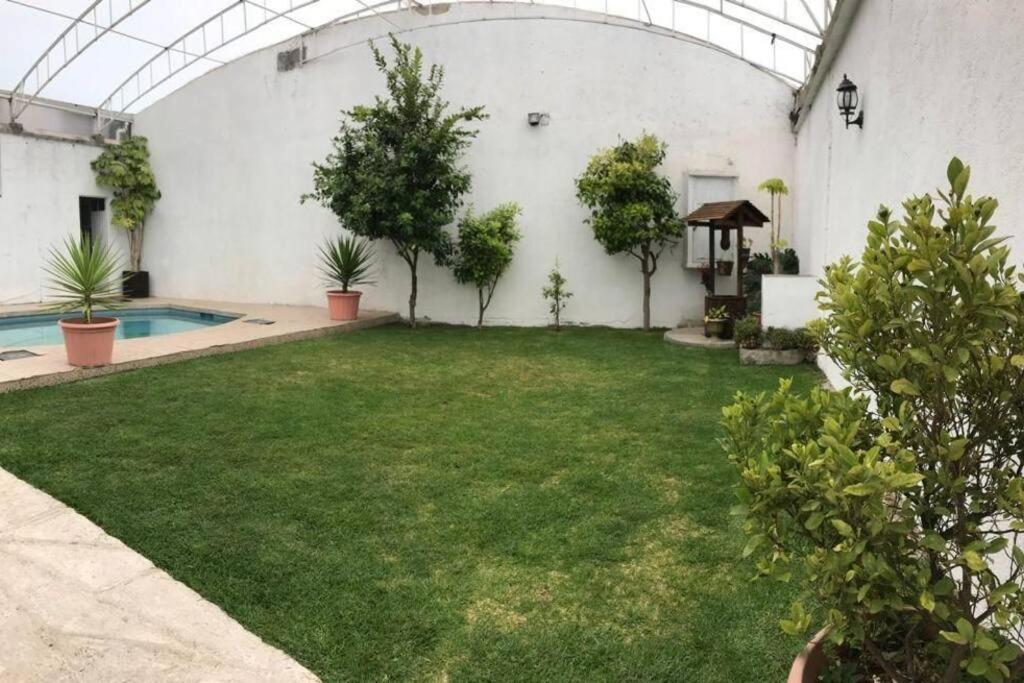 un patio con piscina y un patio con plantas en Casa con amplio jardín y alberca, en Tenango de Arista