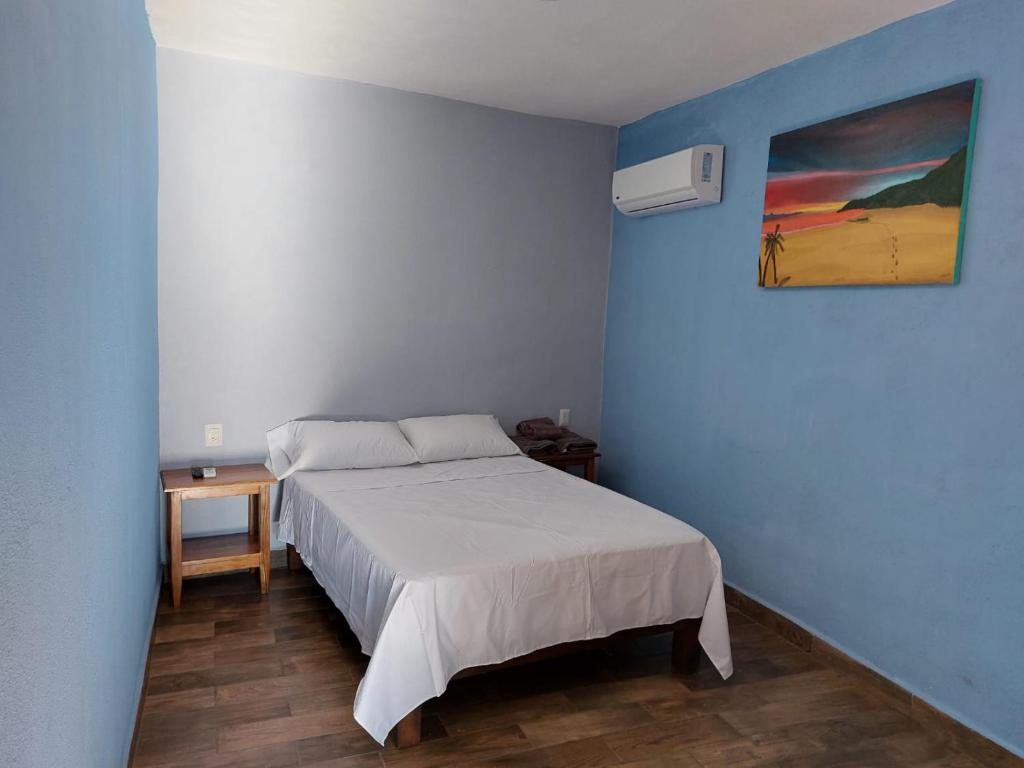 ein Schlafzimmer mit einem Bett und einem Wandgemälde in der Unterkunft LA CASA AZUL DE SAMARA in Barrio Nuevo