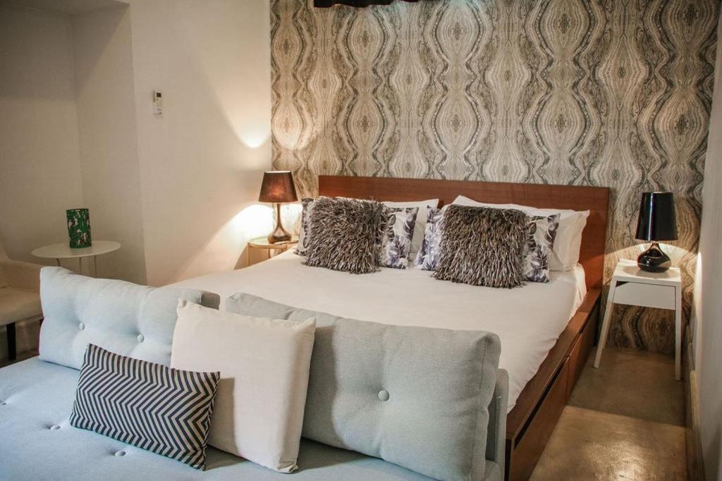 een slaapkamer met een wit bed met kussens en een bank bij AmazINN Places Rooftop and Jacuzzi VII in Panama-Stad